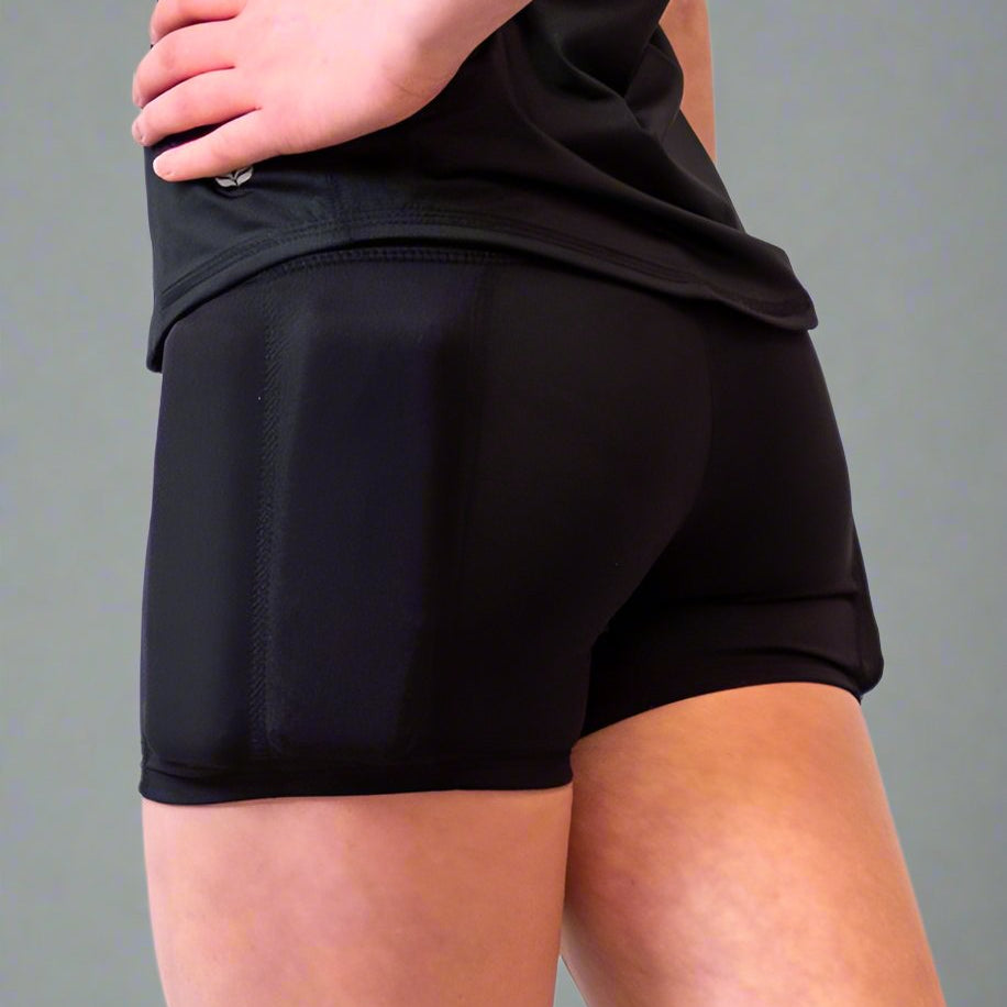 Girl standing showing her side of the body, wearing the black weighted short sleeves with weights on the arms and weights on the side of the leg, with the weights on the hip. Close up picture of the weights on the left leg.