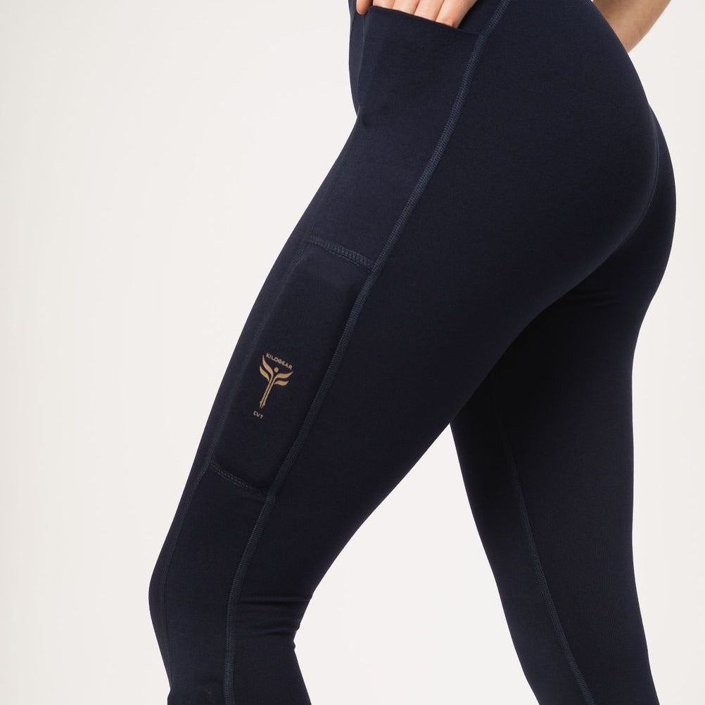 Up close picture of the navy legging with the upper weight pocket and hand in cell phone pocket off the hip