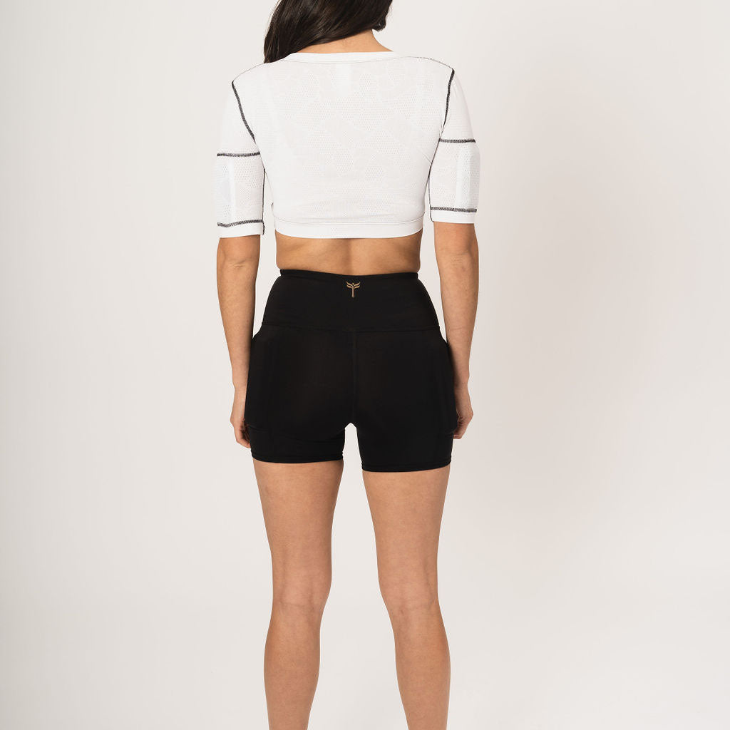 Woman wearing white crop top and black kilogear cut weighted shorts rear view