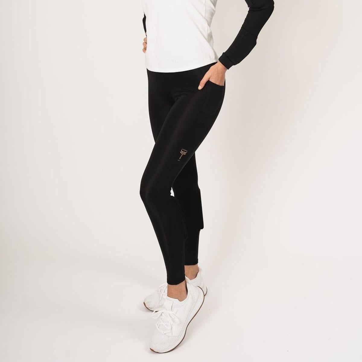 Woman wearing the black weighted booty lift legging. Hand in the top cell phone pocket on the side of the leg.  The weights in the booty lift legging are found on the back side of the calves.