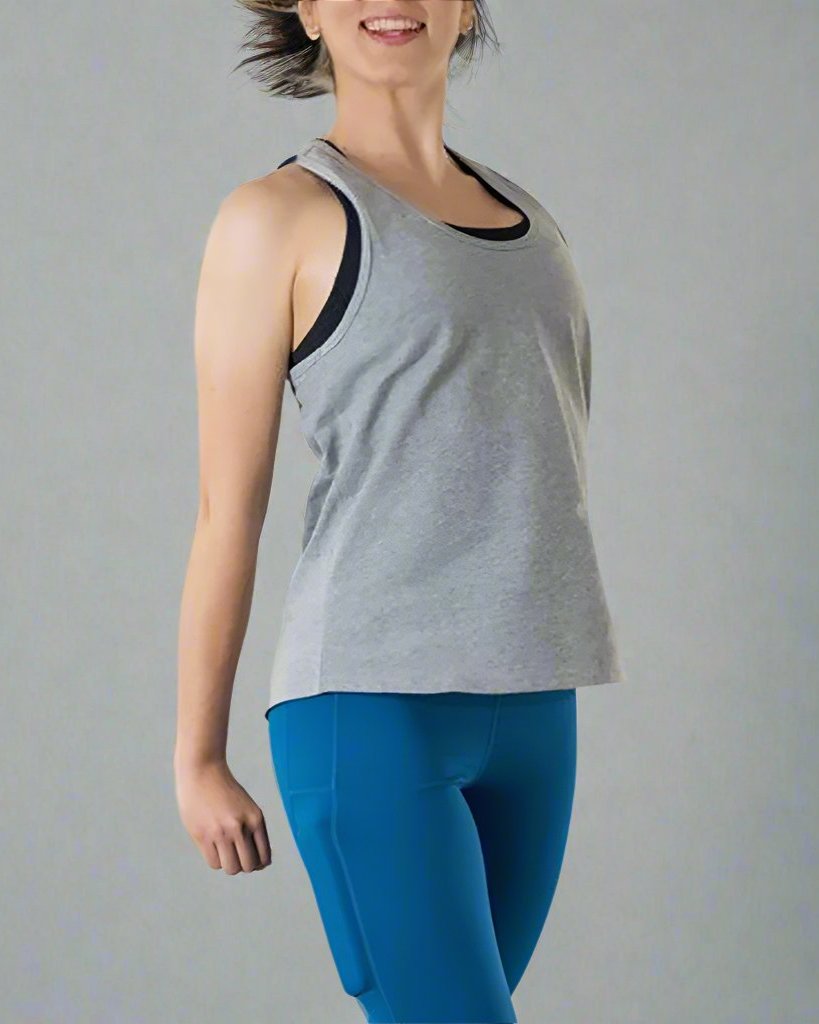 Girl wearing grey tank top with her arms to the side. Tank has scoop neck. 