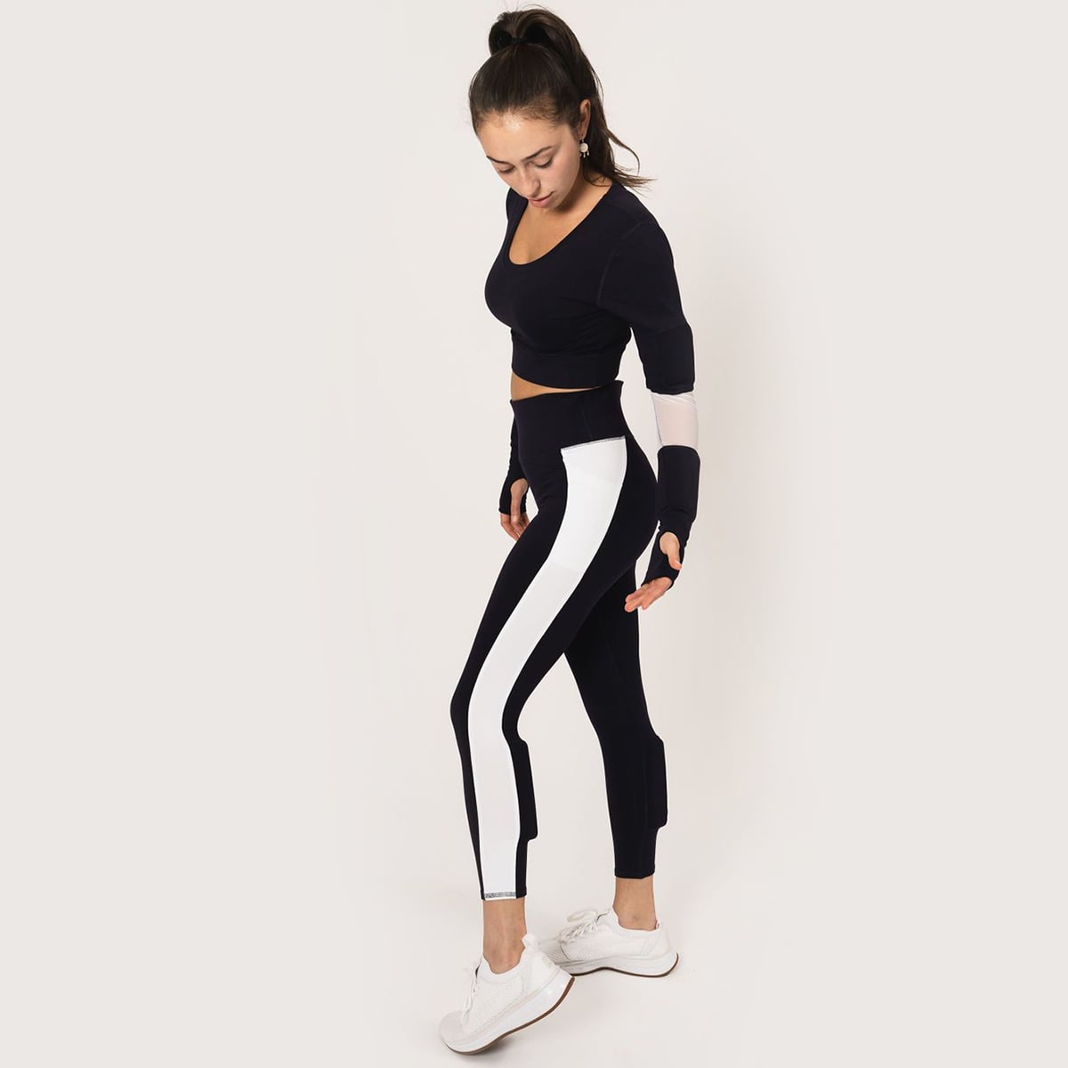 Model wearing the long sleeve scoop neck weighted shrug in navy with white accents and the weighted navy with white strip down the leg booty lift legging with weights on the calves.