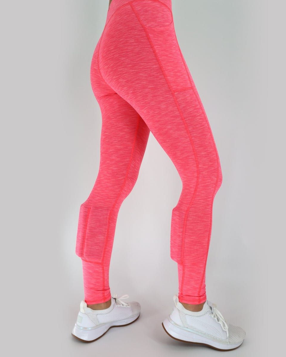 rear view. Woman wearing the heather coral weighted booty lift legging. Hand on the hip. The weights in the booty lift legging are found on the back side of the calves.