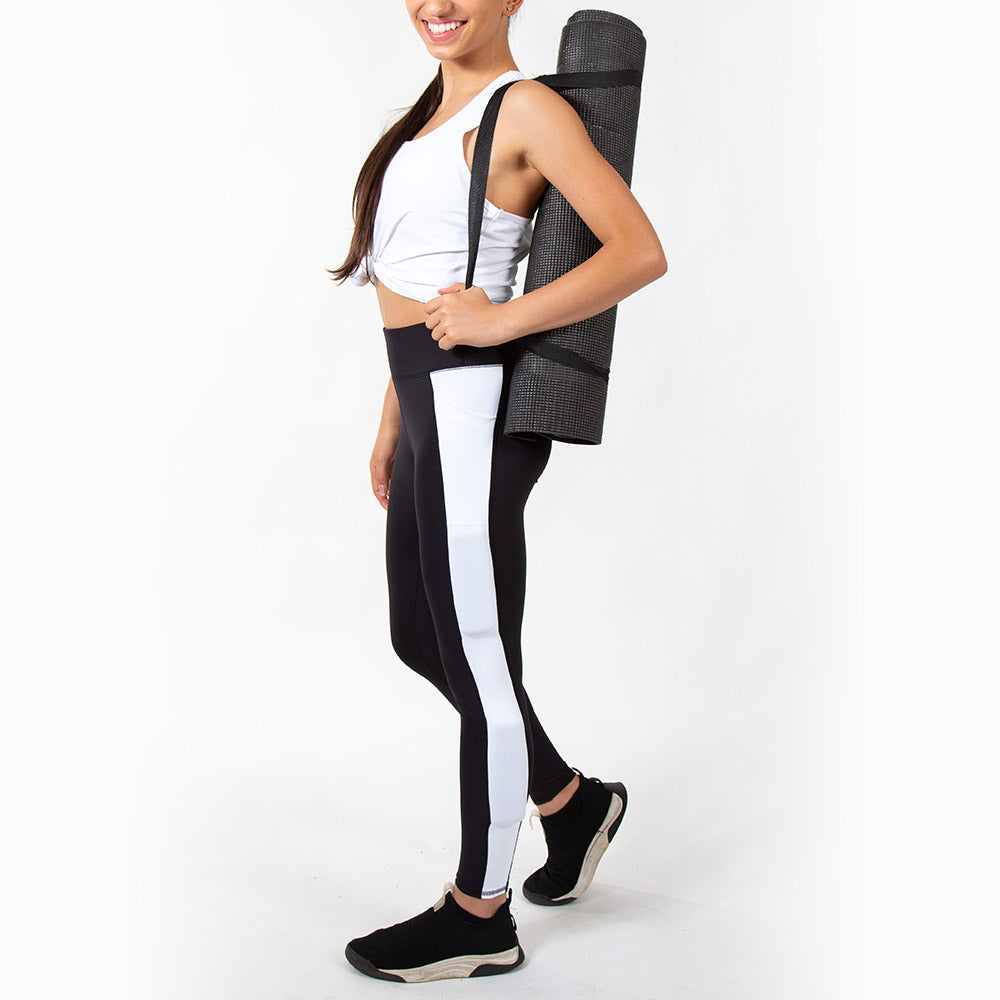 girl holding yoga mat wearing black kilogear cut legging with white strip down the leg, showing weight in the calf weight pocket and quad weight pocket, side view