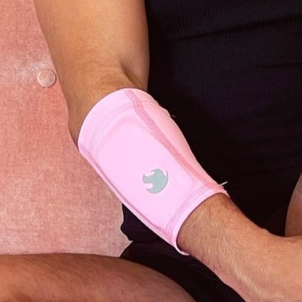 Image showing right arm with the pink arm band on the forearm with weights in the band, showing the silver torch flame in the center. 