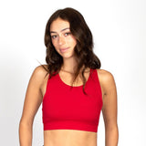 Woman wearing the red sports bra with ribbed texture and elastic trim around the bottom.