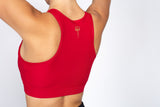 Rear facing image of the red sports bra with razor back and kilogear cut logo in the center back