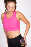 Woman wearing the hot pink sports bra with ribbed texture and elastic trim around the bottom.