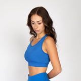 Woman wearing the royal blue sports bra with ribbed texture and elastic trim around the bottom.