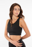 Woman wearing the black sports bra with ribbed texture and elastic trim around the bottom.