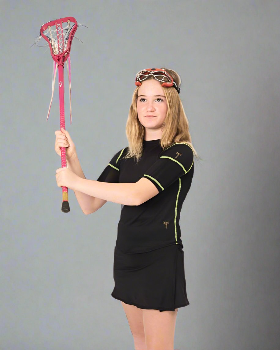 Girl wearing lacrosse goggles and holding lacrosse stick in the weighted black short sleeve with lime green stitching. She has on the black skort and weights in the bicep pockets.