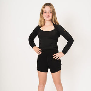 Girls wearing rapid performance shorts with weights on the side (quads) she is standing with her hands on her hips wearing the weighted arm shrug. Front view.