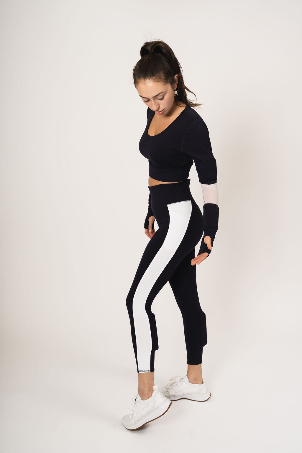 Model wearing the long sleeve scoop neck weighted shrug in navy with white accents and the weighted navy with white strip down the leg booty lift legging with weights on the calves.