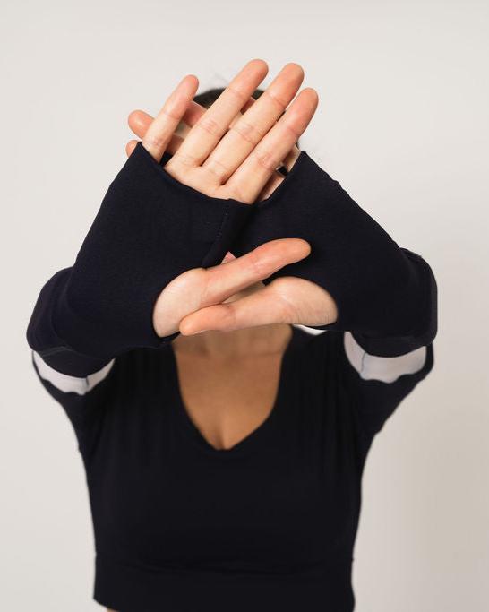 Model is holding her hands up, showing the long sleeve has thumbs holes and when worn, the arm sleeve goes over the knuckles and thumb