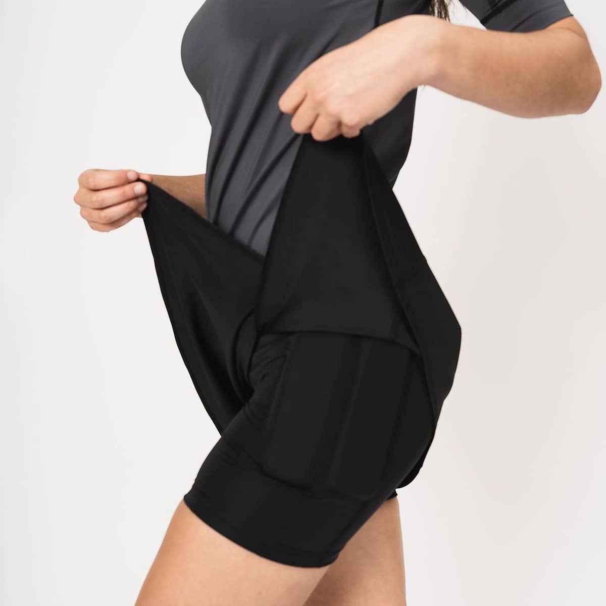 Up close image of woman lifting the skort to show the weighted shorts under the skort