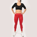 Showing black crop top with scoop neck. Two weight pockets on  the biceps of the arm., front view. Also wearing red weighted just shine leggings, showing weights on the side of the leg above the knee and below the knee.